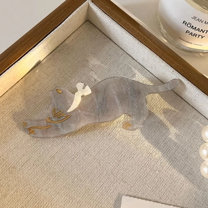Detail of stretching cat hair clip with grey marble texture and gold bird accents