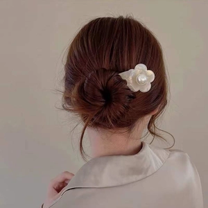 Elegant french acetate flower hair pin with pearl inlay on a stylish brown bun hairstyle