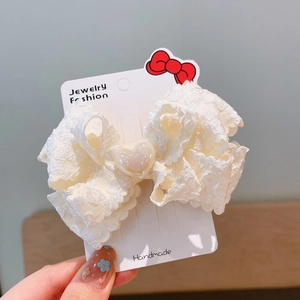 Close-up of cream lace bow hair clip with pink resin heart on handmade display card