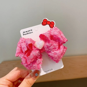 Detailed view of pink lace bow hair clip with a pearly heart bead on a display card