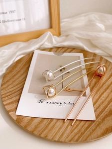 Detailed view of U-shaped hair pins with geometric metal coils and white pearls