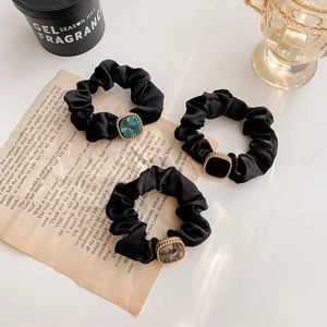 Tre elastici in raso nero con fibbie quadrate in resina vintage su sfondo estetico