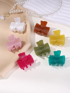 Detailed close-up of colorful jelly-toned acetate bow hair clips on a textured tray