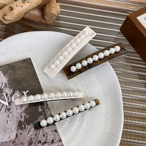 Détail de barrettes à cheveux en acétate fait main avec perles sur un plateau