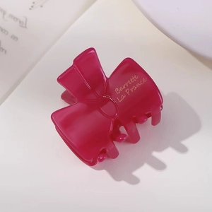 Detail of rose pink acetate bow hair clip featuring golden La France engraved text