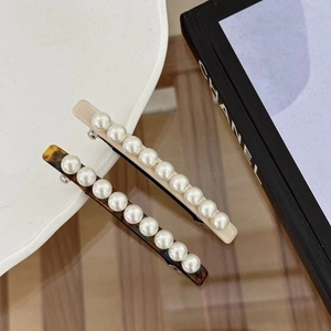 Gros plan de barrettes à cheveux en acétate beige avec perles élégantes pour femmes