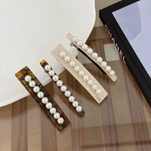 Détail de barrettes en acétate avec perles incrustées et gravure dorée faite main