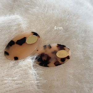 Detail view of 4cm tortoiseshell acetate hair clips with golden oval logo plate