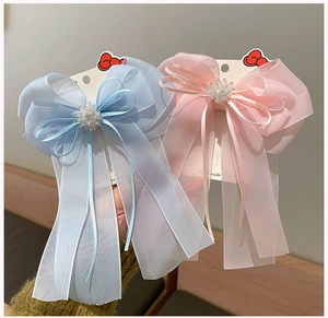 Détail de grandes pinces à cheveux noeud en organza rose et bleu avec fleurs perlées