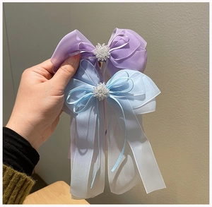 Détail de nœuds à cheveux en organza faits main avec de longs rubans et des perles blanches