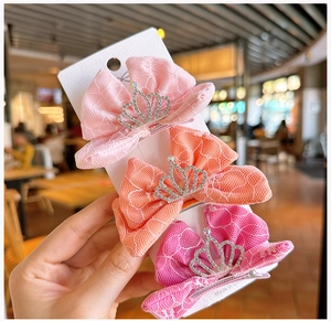 Detalle de tres pinzas de lazo de malla con coronas de strass para niñas en rosa y naranja
