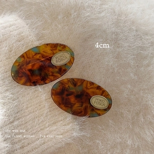 Detail of tortoise shell acetate hair clips with gold metal plates on plush background