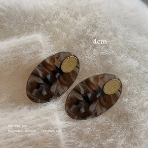 Macro shot of 4cm brown marble acetate hair clip featuring a gold logo metal plate