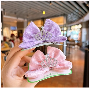 Detalle de horquillas de lazo de encaje con coronas de diamantes rosa y púrpura
