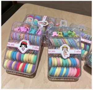 Detail of colorful hair accessory set with elastic bands and mini clips in a storage box