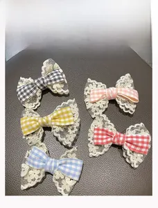 Detail of five plaid bow hair clips with double-layer lace on grey leather texture