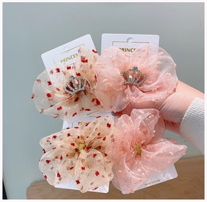 Dettaglio di elastici per capelli in tulle rosa con corona di strass e pois fini