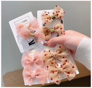 Dettaglio di fermagli per capelli a fiocco in rete rosa e beige con stampe floreali