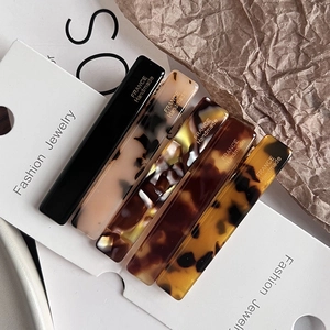 Close-up of 5-piece acetate hair clips with leopard and marble patterns on display card