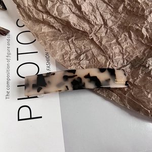 Detailed macro view of acetate hair clip featuring tortoise shell pattern and gold handmade text