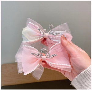 Detail van roze mesh strik haarspelden met kristallen kronen en parelranden afwerking