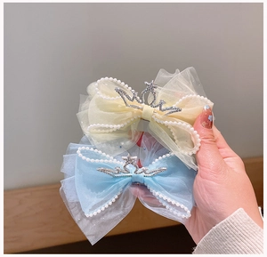 Detail van mesh strik haarclips met parels en strass kronen in geel en blauwe kleuren