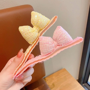 Vue détaillée de grandes barrettes à nœuds pailletés en couleurs rose et jaune clair