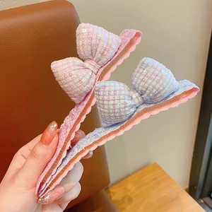 Vue détaillée des pinces banane à nœud pailleté en rose et motifs bleu clair