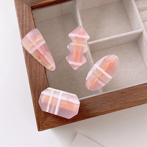 Detailed view of pink acrylic geometric hair clips with grid patterns in a wooden box