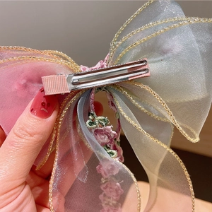 Close-up of children's embroidery mesh bow hair clip with duckbill clip and pink flower detail