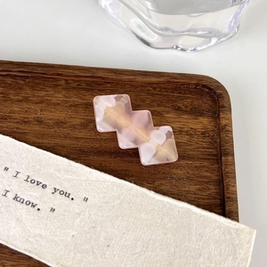 Close-up of pink and white marble geometric hair clip on a wooden tray background