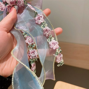 Detail of embroidered floral organza ribbon with delicate iridescent mesh for hair clips