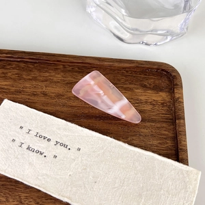 Detailed macro view of pink marble resin hair clip with elegant geometric triangular design
