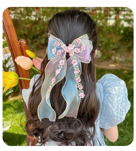 Detailed view of large embroidered tulle bow hairpin with floral accents for girls