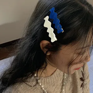 French style wavy acetate hair clips in blue and beige worn on woman's side hair