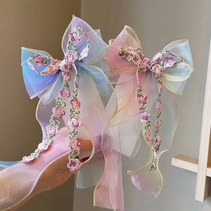 Detailed close-up of embroidered mesh bow hair clips with gradient colors and floral lace
