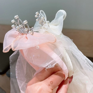 Detail of pink and white crown headband featuring layered mesh bow and long tulle veil