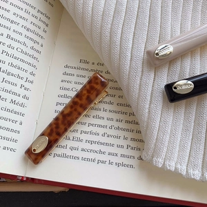 Close-up of leopard pattern and cream acetate hair clips on vintage book pages