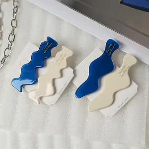 Elegant wavy acetate hair clips set in blue and cream white with gold lettering