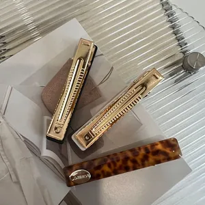 Detailed view of leopard acetate hair clip and gold metal hairpins on a chic tray