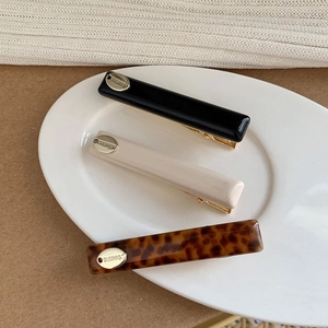 Detail view of rectangular hair clips in leopard, cream, and black with gold metal accents