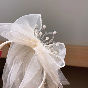 Macro view of multi-layer tulle bow headband with pearl crown and rhinestone detailing