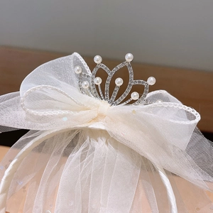 Close-up of white lace bow headband with a silver pearl crown and sparkling veil details