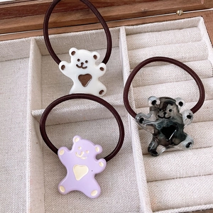 Detail of cute resin bear hair ties in cream, lilac, and marble on a soft beige velvet lining
