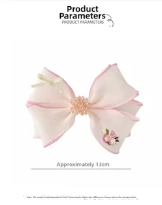 Detail showing pink bow hairclip with floral embroidery and beads, size 13cm width