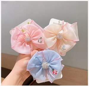 Close-up of embroidered floral organza hair bows with rhinestones on a display card