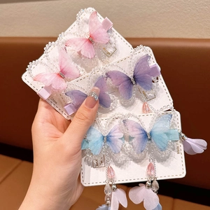 Three 3D butterfly hair clips with rhinestones and long tassels in pink, purple, and blue