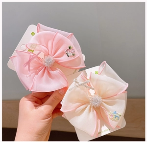 Close-up of organza bow hair clips with delicate embroidery and beaded flower center