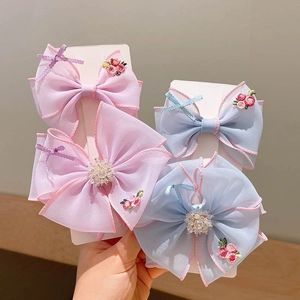 Set of four embroidered floral bow hair clips in soft pink and light blue colors