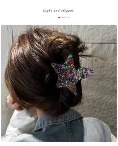 Macro detail of star-shaped hair claw clip with colorful sequins and metal spring